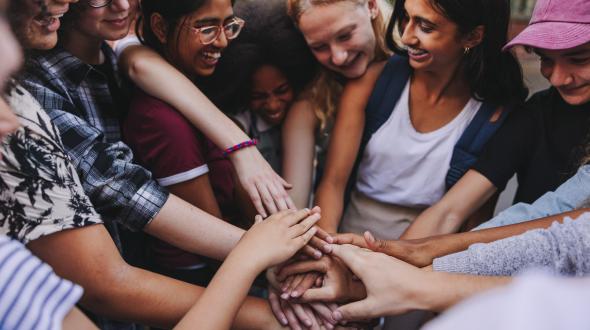 students of different cultures holding hands in a huddle