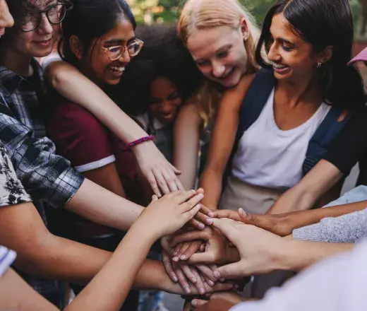 students of different cultures holding hands in a huddle