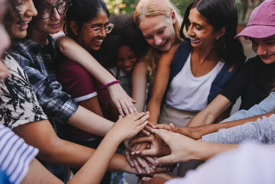 students of different cultures holding hands in a huddle